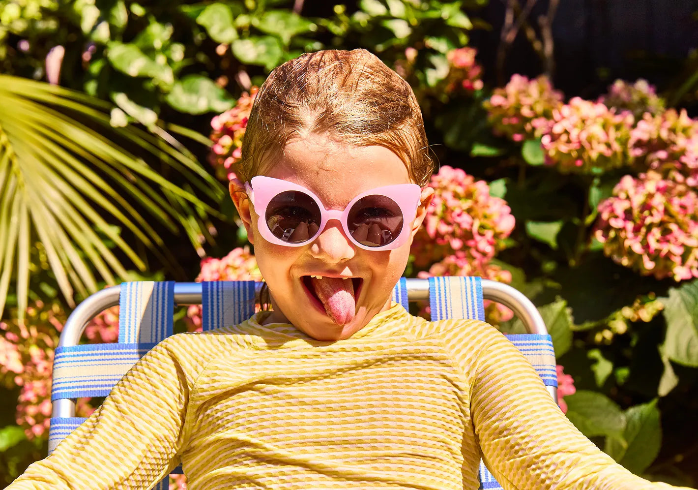 Kid relaxing on a lawn chair wearing pink sunglasses